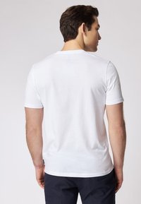 T-shirt bianco in cotone con maniche corte, scollatura rotonda e una texture morbida. Presenta un'etichetta sottile all'orlo e una vestibilità comoda.