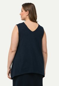 Niebieski top bez rękawów z dekoltem w kształcie litery V i luźnym krojem, z zaokrąglonym dołem i miękkim, lekkim materiałem.