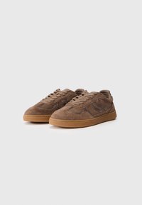Braune Wildledersneaker mit glatter Textur, Gummisohle und gesteppten Akzenten an den Seiten. Mit Schnürverschluss.
