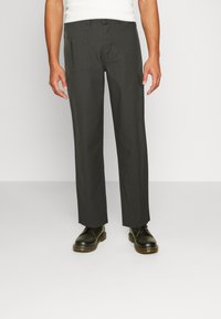 Dunkelgraue Cargo-Hosen aus strapazierfähigem Stoff mit Seitentaschen, geraden Beinen und einem flachen Bund. Dazu schwarze Schnürschuhe.