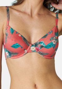 Reggiseno corallo con stampa floreale che presenta foglie verdi e fiori bianchi. Tessuto morbido con spalline regolabili e supporto con ferretto.
