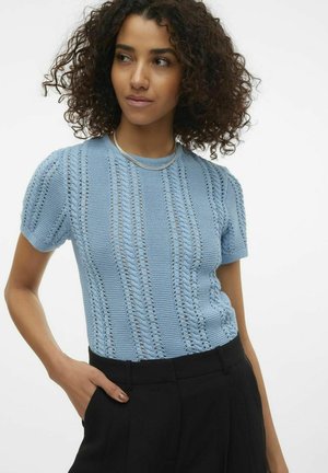 Lichtblauw gebreid T-shirt met korte mouwen, voorzien van gestructureerde verticale strepen en een ronde halslijn. Gecombineerd met zwarte broek.