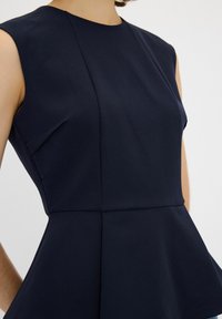 Vestito senza maniche blu navy con scollo tondo, vestibilità sartoriale e dettaglio peplum in vita. Tessuto liscio con una texture opaca.