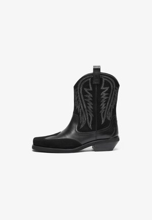 Botas de cowboy pretas com acabamento em couro liso e camurça, apresentando padrões bordados em prata e um salto empilhado. Design de bico arredondado.