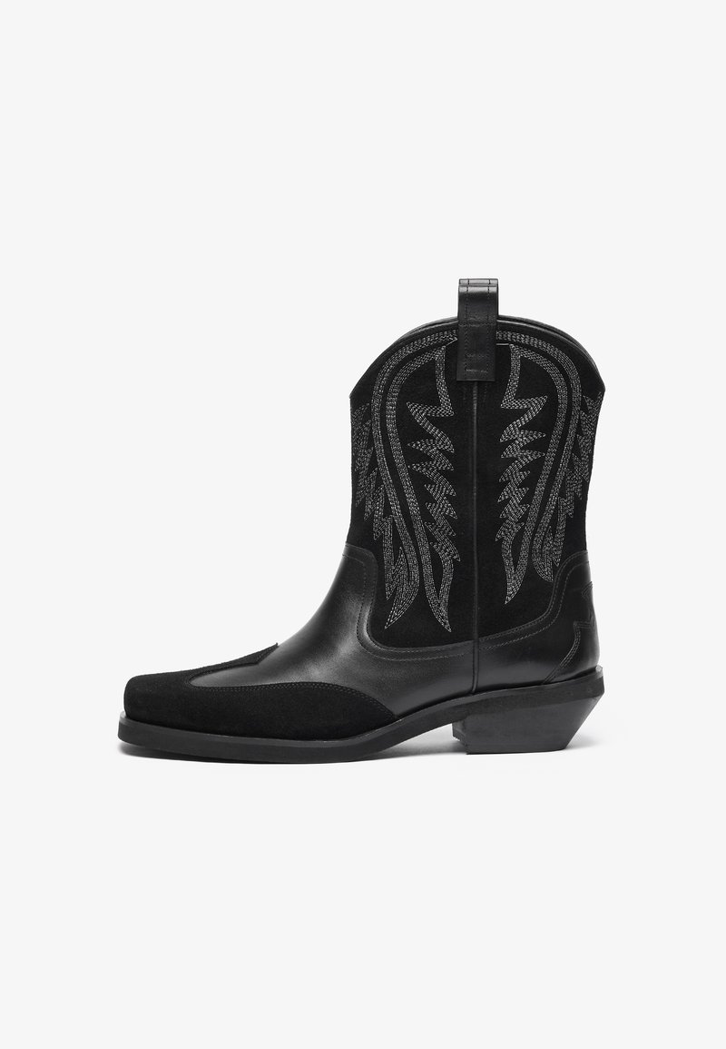 Botas de vaquero negras con un acabado de cuero liso y ante, que presentan patrones bordados en plata y un tacón apilado. Diseño de punta redonda.