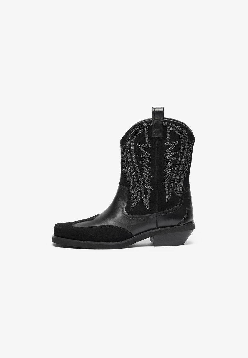 Svarte cowboystøvler med en glatt lær- og semsket finish, med sølv broderte mønstre og en stablet hæl. Rundt tådesign.