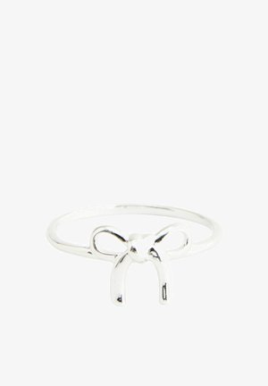 Silver hoop earrings and a silver ring with a bow design. The model has dark, wavy hair and is wearing a light blue knitted sweater.