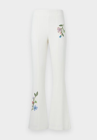 Άσπρο παντελόνι καμπάνα με ψηλή μέση, διακοσμημένο με κεντητά λουλουδάτα σχέδια κοντά στο δεξί ισχίο και στο κάτω μέρος του αριστερού ποδιού.