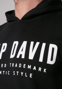 Sudadera negra de algodón, que presenta un gran texto blanco que dice "UP DAVID" y un texto más pequeño debajo, con una capucha cómoda.