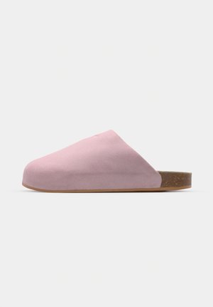 Chaussure slip-on en daim rose avec un bout arrondi, semelle plate en liège et texture lisse. Design minimaliste sans matériel ou motifs visibles.