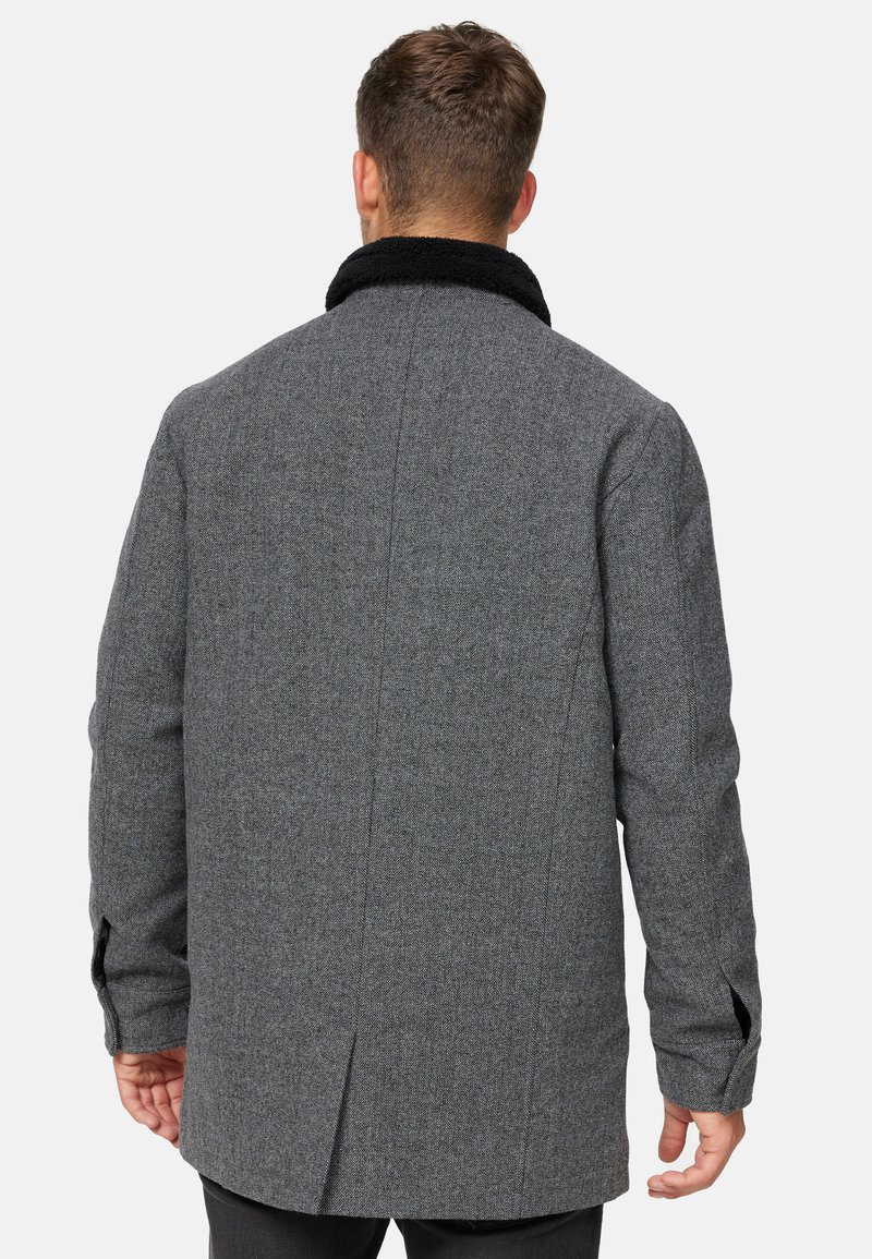 Grau gemischter Wollmantel mit einem schwarzen Fake-Fur-Kragen, gerade geschnitten, mit seitlichen Nähten und langen Ärmeln, sichtbarem Rückenschlitzdetail.