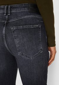 Vaqueros de mezclilla de lavado oscuro con ajuste de talle medio, que cuentan con un bolsillo trasero y un acabado texturizado. La etiqueta en la cinturilla dice "Marc O'Polo."