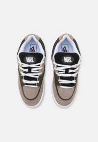 VANS kenkät, joissa on sekoitus tanin, oliivin ja mustan mokkanahan. Sisältää valkoiset nauhat, pyöreän logopatchin ja pehmeän vuorauksen. Matala malli.