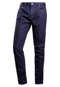 Úzké tmavomodré džíny s oranžovými stehy, pěti kapsami a předním zapínáním na knoflík. Hladká textura; klasický design.