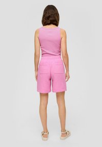 Roze geribbelde tanktop gecombineerd met roze shorts met een gestructureerd ontwerp, elastische tailleband en twee achterzakken.