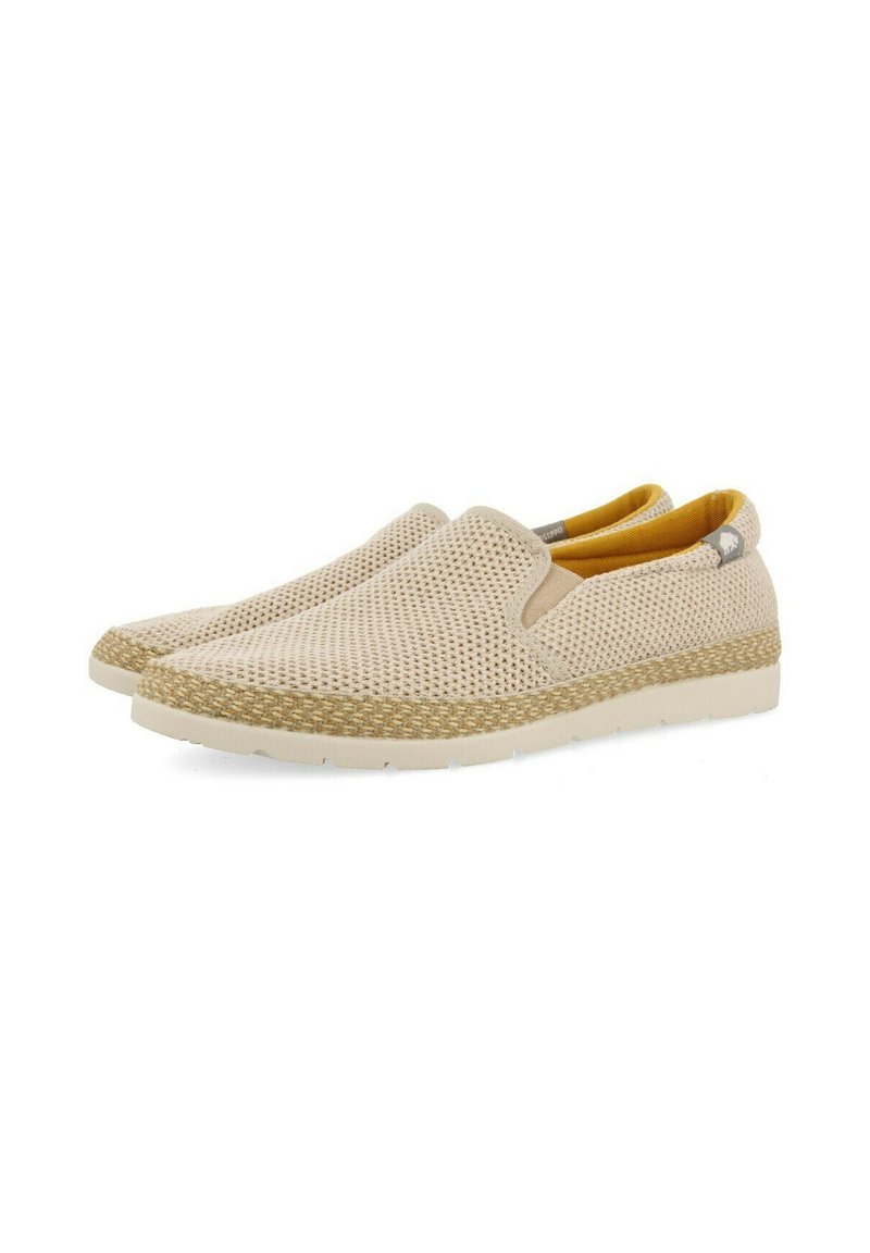 Zapatos de slip-on beige con parte superior de malla, forro interior amarillo y suela de yute trenzado. Presentan una punta redondeada y suela de goma.