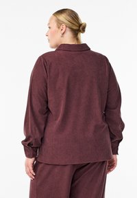 Burgundijas krāsas korduroja krekls ar apkakli, garām piedurknēm un pogājamiem aproču galiem. Mīksta tekstūra ar smalku ribu rakstu.
