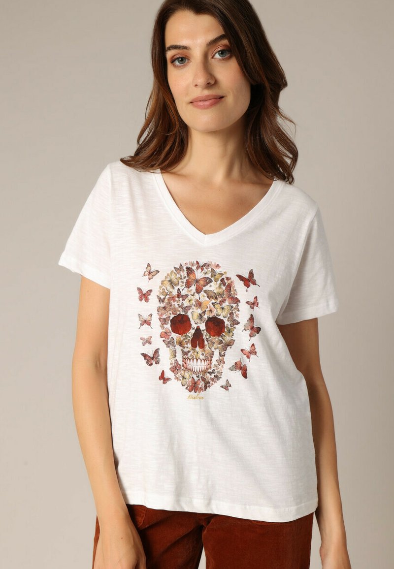 T-shirt blanc à col en V avec un design graphique d'un crâne composé de papillons dans des tons de rouge, jaune et marron. Tissu doux et léger.