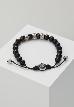Bracelet noir à perles avec trois anneaux décoratifs en argent et cordon noir réglable orné d'un fermoir à emblème de lion en argent.