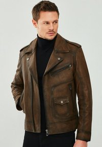 Veste de moto en cuir marron avec fermeture éclair à l'avant, boutons-pression et poches latérales. Comprend un col structuré et des épaulettes.
