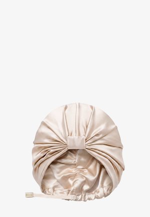 Bonnet de sommeil en satin beige avec un design froncé et noué et une sangle réglable étiquetée "Silke" sur fond blanc.