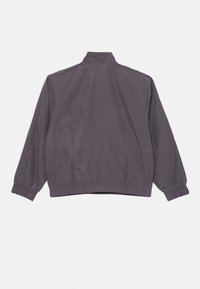 Siva jakna z elastičnimi manšeti in visokim ovratnikom, nekoliko ohlapnega kroja, z gladko teksturo in minimalističnim dizajnom.