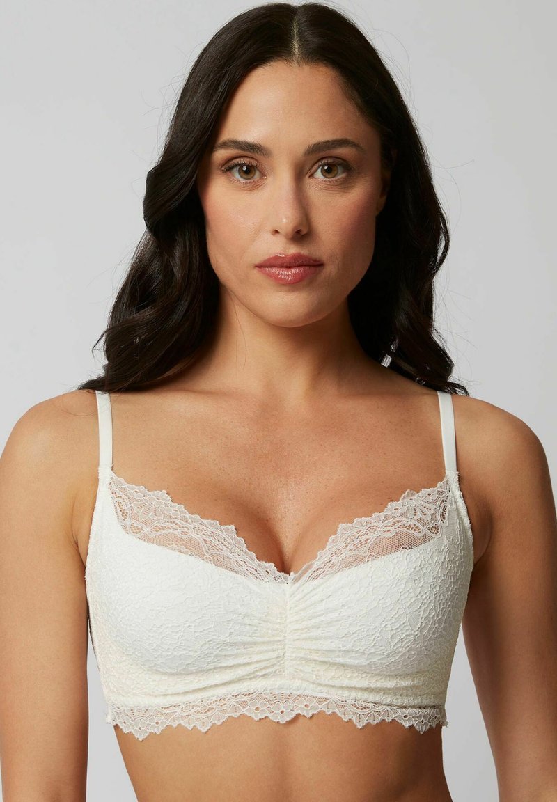 Soutien-gorge bianco in pizzo con un motivo floreale, tessuto morbido, scollatura profonda, centro arricciato e spalline regolabili con un delicato bordo in pizzo.