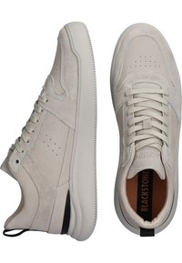 Baskets en daim beige clair avec lacets à l’avant, détails perforés, col rembourré et semelle en caoutchouc blanche, vues de côté et de dessus.