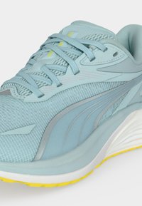 Αθλητικό παπούτσι ανοιχτού μπλε χρώματος με διχτυωτό και συνθετικό πάνω μέρος, κλείσιμο με κορδόνια, παχιά λευκή ενδιάμεση σόλα και κίτρινη λαστιχένια εξωτερική σόλα.