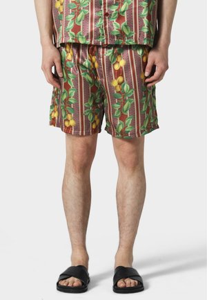 Shorts légers à motifs avec des feuilles vertes et des fruits jaunes sur fond rouge. Dotés d'une taille élastique et d'une coupe décontractée.