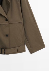 Brown, tailored jacket with a double-breasted design, textured fabric, large lapels, side pockets, and a belted waist with a black buckle.