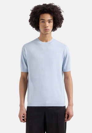 Hellblauer, kurzärmeliger Strickpullover mit Rundhalsausschnitt und dezentem Texturmuster. Kombiniert mit dunkel, locker sitzenden Hosen. Einfaches Design, ohne Muster.