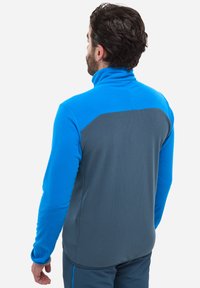 Pullover en polaire avec un col haut, présentant une partie supérieure bleue et un bas arrière gris. Tissu texturé avec un bloc de couleur contrastant.