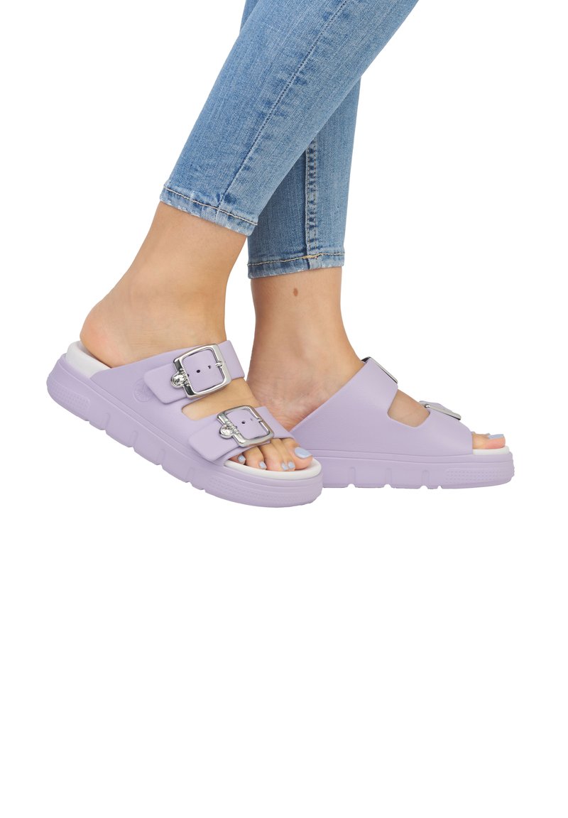Lavender slide sandals with dual adjustable buckles and a thick, textured outsole. Smooth upper material with a curved design and open toe.