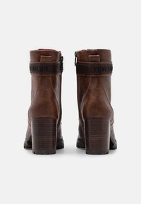 Stivali alla caviglia in pelle marrone con finitura testurizzata, dotati di un tacco alto, zip laterale e fasce con logo "TOM TAILOR" in rilievo lungo la caviglia.