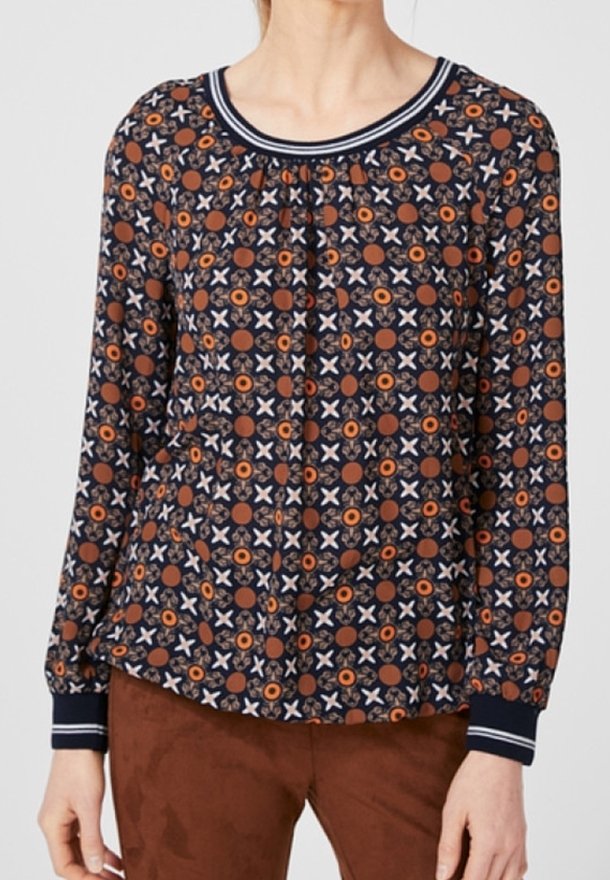 Blouse à manches longues en marine foncé avec un motif circulaire et croisé en orange et blanc, dotée d'un col rond à côtes et de poignets élastiques.