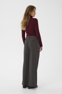 Un col roulé bourgogne et un pantalon large à taille haute rayé gris avec un tissu texturé, comportant un détail de poche arrière.