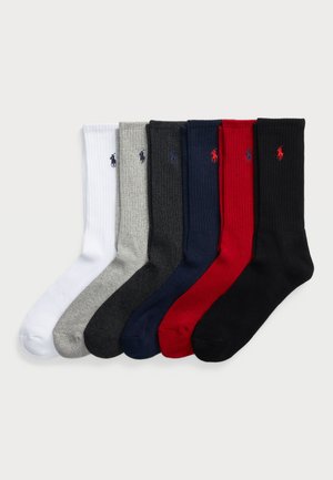Six pairs of ribbed socks in white, gray, navy, red, and black, featuring a small logo on each sock. Soft, stretchy cotton blend material.