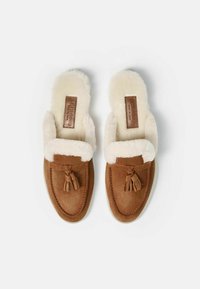 Pantofole in suede marrone con fodera in pelliccia sintetica, punta chiusa e dettaglio con nappine, dotate di suola imbottita per comfort e calore.