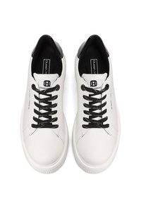 Sneaker in pelle bianca con dettagli neri, punta tonda e lacci neri. Presenta una suola testurizzata e un logo sulla linguetta.