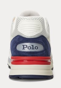 Vit sko med marinblå mocka och röda accenter. Nät- och släta paneler vid hälen, logotypdetalj i silver. Texturerad yta med dämpad sula.