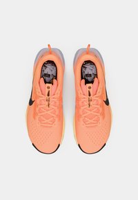 Roze sportieve schoenen met een bovenwerk van mesh stof, ronde neus, zwart Nike logo en textuuraccenten; heeft een doorschijnende zool.