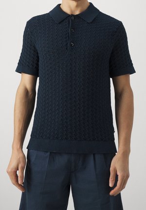 Polo de punto en navy con mangas cortas, un patrón de rombos texturizado y una tapeta de tres botones en el cuello. Corte casual con dobladillo acanalado.