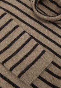 Beżowy sweter z ciemnobrązowymi paskami, wykonany z miękkiego dzianinowego materiału. Posiada wywinięty dekolt i kieszeń z detalem w paski.