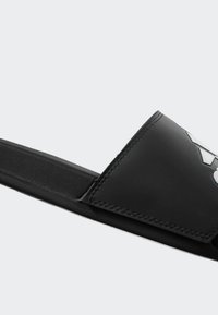 Pánské černé skládací sandály vyrobené z odolného syntetického materiálu. Mají široký pásek, texturovaný povrch a detail loga v kontrastní barvě.