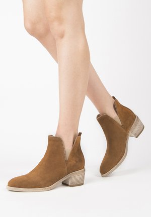 Stivaletti in suede marrone con un leggero tacco, pannelli laterali elasticizzati e cuciture decorative lungo il bordo superiore, con un tacco texturizzato.