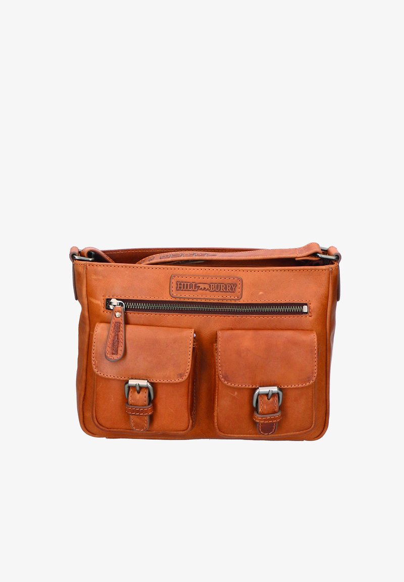 Sac à épaule en cuir tan avec deux poches avant, compartiment principal zippé et un patch logo de marque. Présente des accents en matériel argenté.