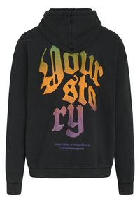 Sort hættetrøje med en stor, farverig grafisk tekst på ryggen med sætningen "Your Story" og mindre tekst nedenunder.