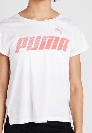 Camiseta blanca de manga corta con un gran logo rosa de Puma en el pecho, llevada por una persona de tono de piel medio y cabello rizado.