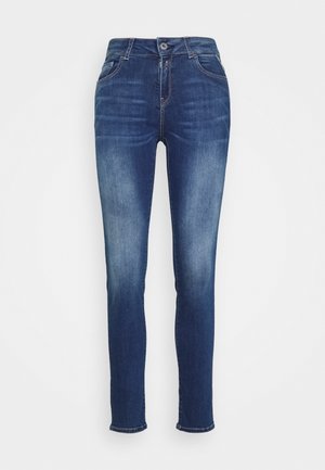 Vaqueros ajustados azul oscuro con detalles desgastados, botón delantero, cierre de cremallera y bolsillos delanteros y traseros sobre un fondo liso.